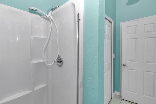 full bath with a shower stall, tile patterned floors, and a textured wall