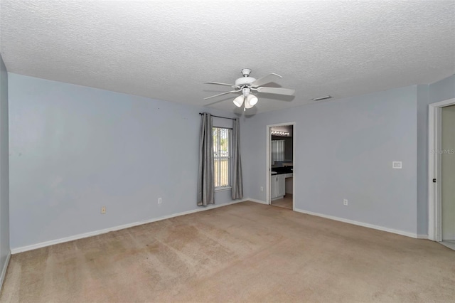 unfurnished room with ceiling fan, light carpet, baseboards, and a textured ceiling