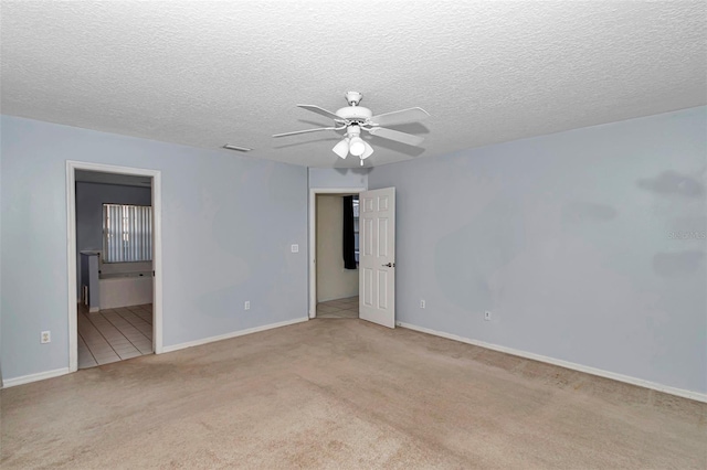 unfurnished bedroom with carpet, baseboards, a textured ceiling, ensuite bath, and a ceiling fan