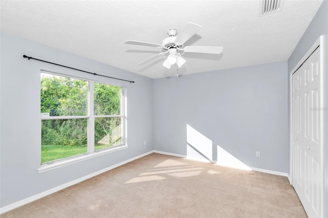 unfurnished bedroom with a closet, carpet, baseboards, a textured ceiling, and ceiling fan