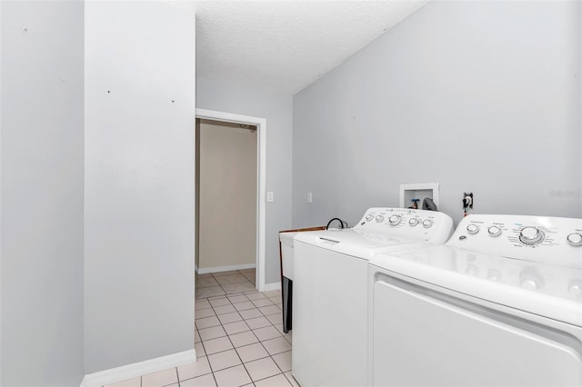 clothes washing area featuring independent washer and dryer, light tile patterned floors, a textured ceiling, and baseboards