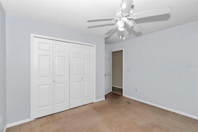 unfurnished bedroom featuring carpet flooring, baseboards, a closet, ceiling fan, and a textured ceiling