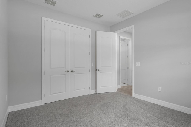 unfurnished bedroom with visible vents, carpet flooring, and a closet