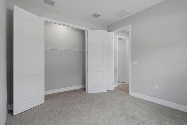 unfurnished bedroom featuring carpet floors, visible vents, and a closet