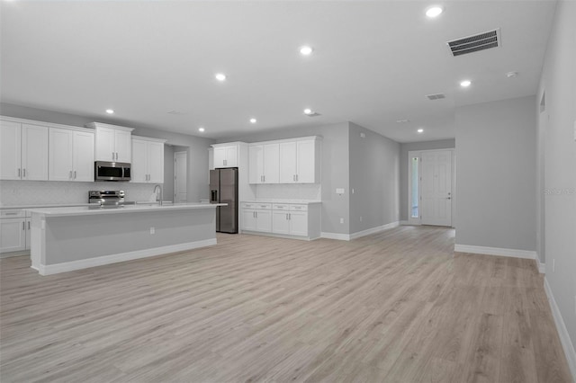 kitchen with visible vents, open floor plan, tasteful backsplash, a sink, and stainless steel appliances