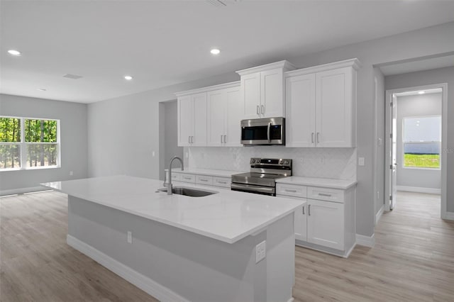 kitchen with appliances with stainless steel finishes, a sink, light wood-style floors, recessed lighting, and baseboards
