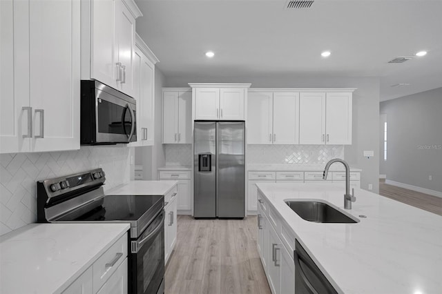 kitchen featuring a sink, light wood finished floors, white cabinetry, and stainless steel appliances