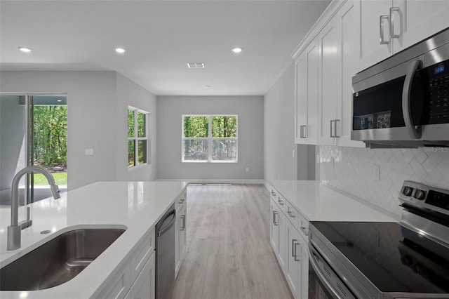 kitchen featuring visible vents, a sink, stainless steel appliances, recessed lighting, and light wood-style flooring
