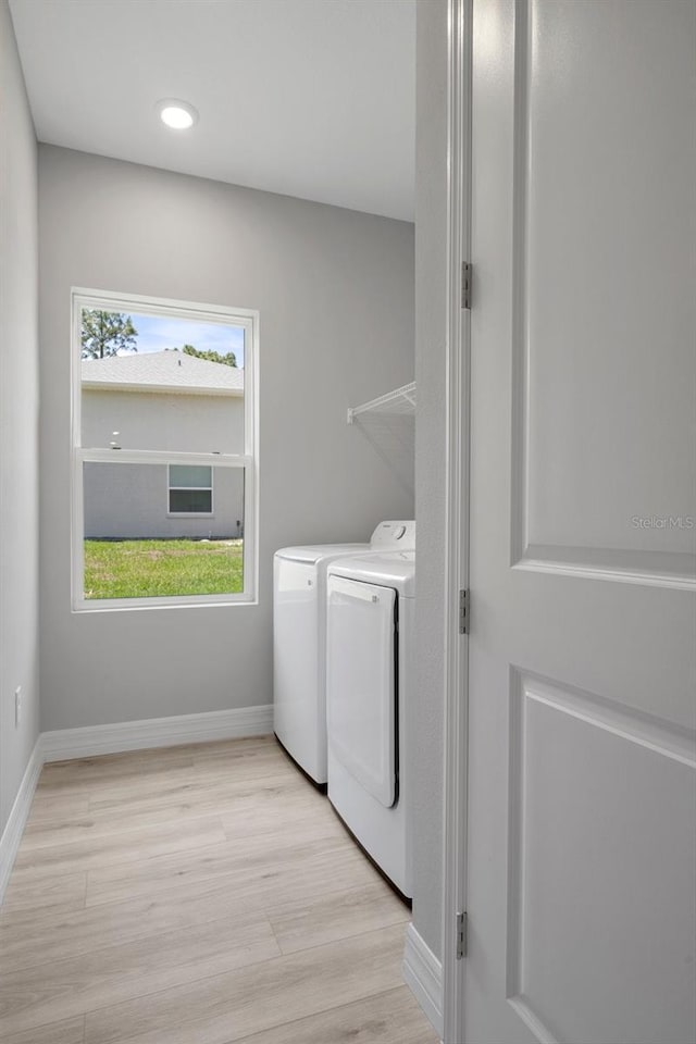 laundry room with baseboards, laundry area, washing machine and dryer, and light wood-style flooring