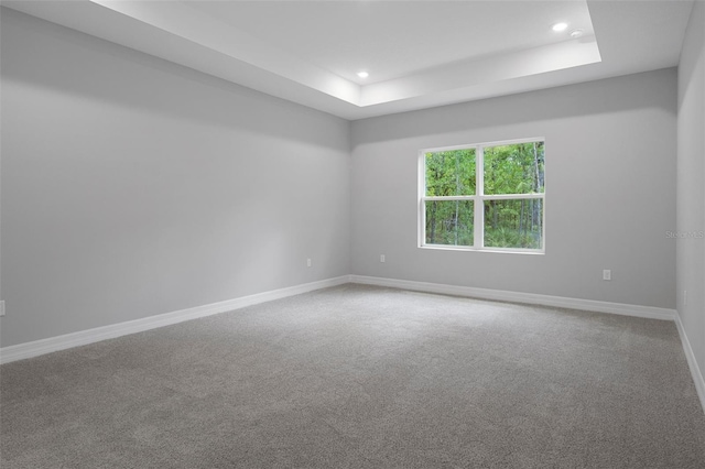 unfurnished room with recessed lighting, a raised ceiling, baseboards, and carpet floors