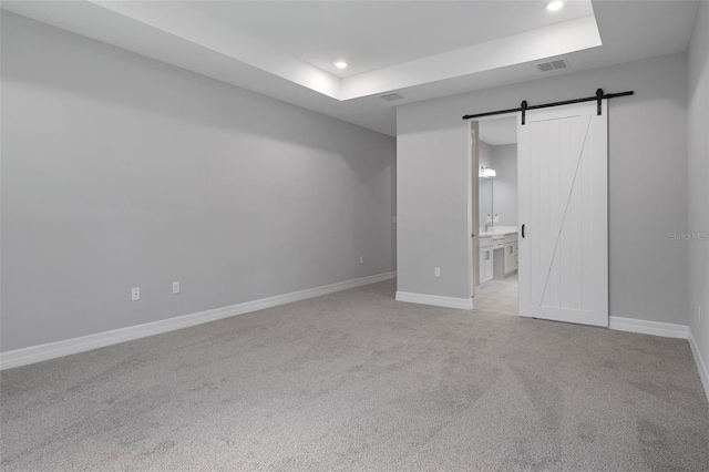unfurnished bedroom with visible vents, a barn door, carpet floors, baseboards, and recessed lighting