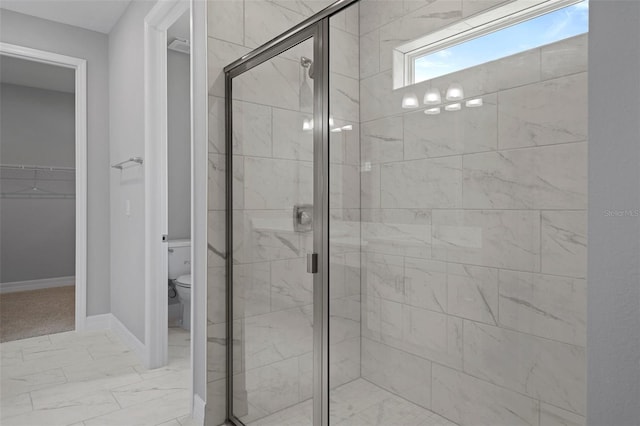 bathroom with a walk in closet, a shower stall, baseboards, toilet, and marble finish floor