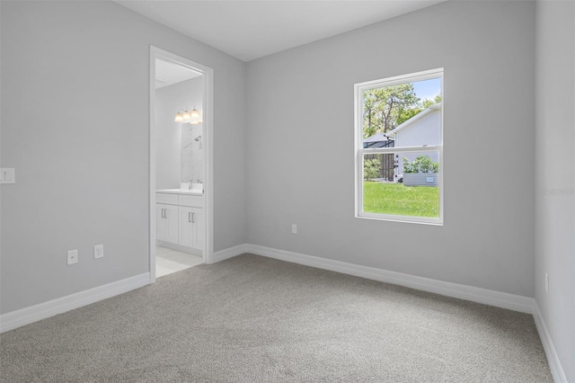 spare room with baseboards, light carpet, and a sink