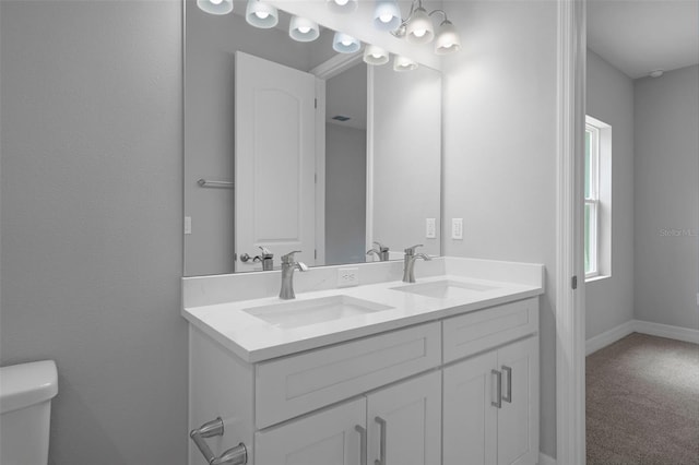 full bathroom featuring a sink, baseboards, toilet, and double vanity
