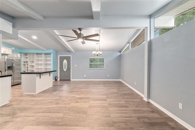unfurnished living room with beamed ceiling, light wood-style floors, baseboards, and ceiling fan with notable chandelier