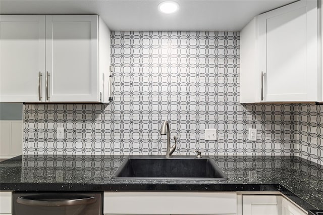 kitchen with white cabinets, dark countertops, dishwasher, a sink, and decorative backsplash