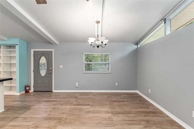 foyer with light wood-type flooring, baseboards, beam ceiling, and a chandelier