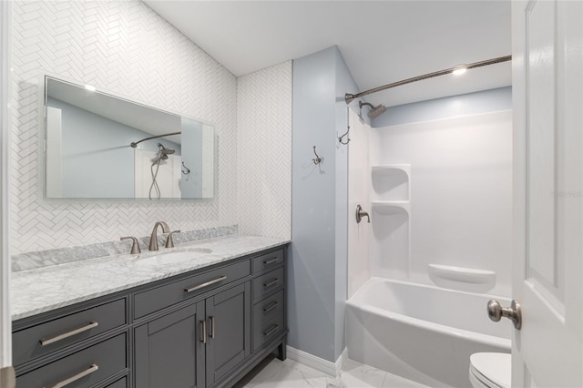 bathroom with  shower combination, toilet, baseboards, marble finish floor, and vanity