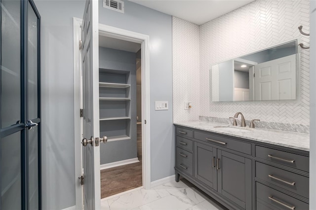 bathroom with decorative backsplash, vanity, marble finish floor, baseboards, and visible vents