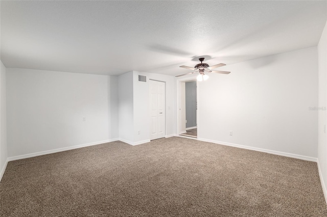 empty room with ceiling fan, carpet floors, visible vents, and baseboards