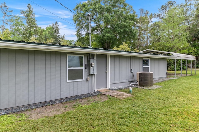 back of house with central AC, a lawn, and metal roof