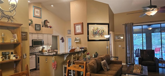 living area featuring dark wood-style flooring, ceiling fan, and high vaulted ceiling
