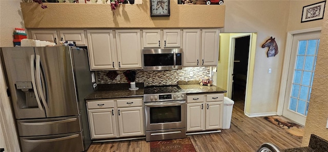 kitchen featuring white cabinetry, decorative backsplash, appliances with stainless steel finishes, a textured wall, and dark wood-style floors