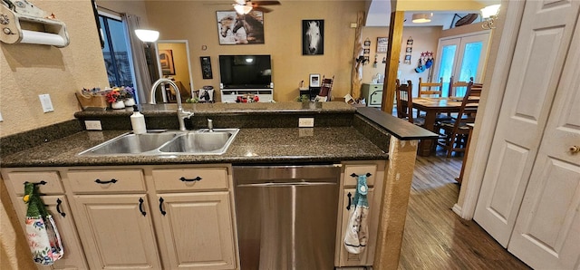 kitchen featuring a sink, a peninsula, stainless steel dishwasher, dark countertops, and dark wood finished floors