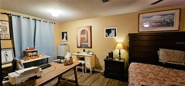 office with baseboards, visible vents, wood finished floors, and a textured ceiling
