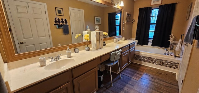 full bathroom with a garden tub, double vanity, a sink, and wood finished floors