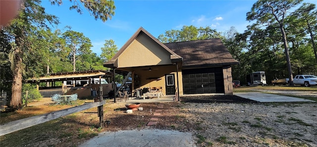 chalet / cabin with a ceiling fan, a garage, stucco siding, and driveway