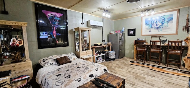 bedroom featuring concrete block wall, an AC wall unit, and stainless steel refrigerator with ice dispenser