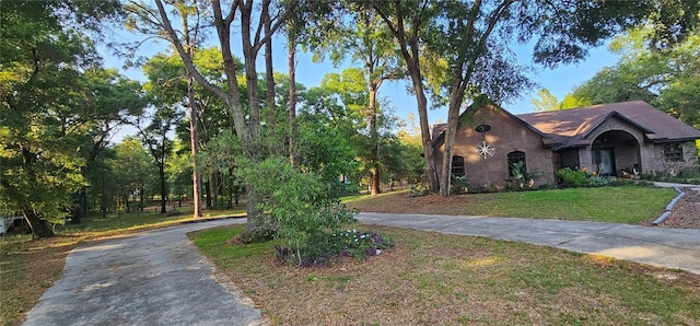 view of front facade with a front lawn, curved driveway, and brick siding