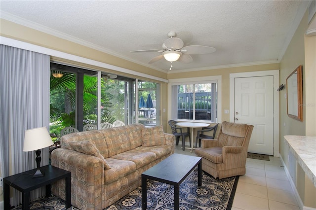 living room with light tile patterned floors, ceiling fan, ornamental molding, and a textured ceiling