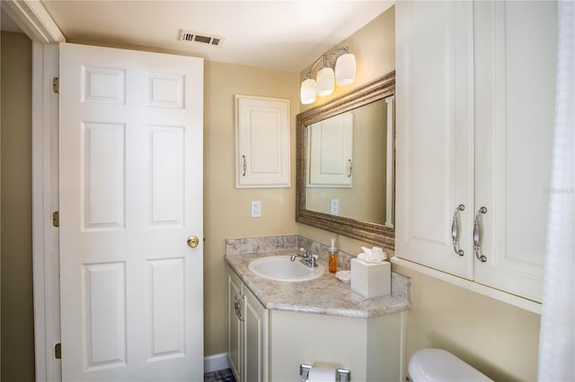 bathroom featuring visible vents, toilet, and vanity