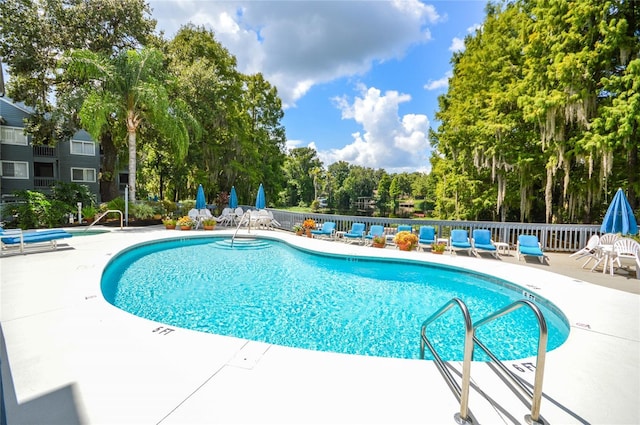 community pool with fence and a patio area
