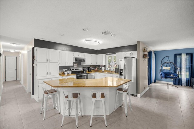 1081 SE 170th Ave, Silver Springs, FL 34488 - kitchen featuring stainless steel appliances, white cabinets, a kitchen breakfast bar, a sink, and baseboards
