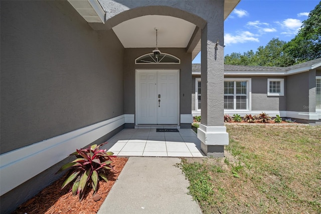 view of exterior entry featuring stucco siding and a yard