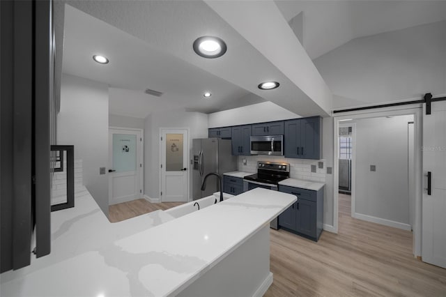 kitchen featuring stainless steel appliances, backsplash, light wood-type flooring, baseboards, and a peninsula
