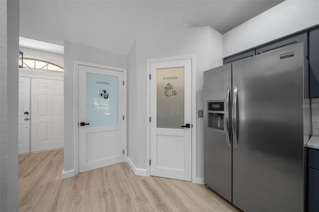 kitchen with baseboards, light wood-style flooring, light countertops, and stainless steel fridge with ice dispenser