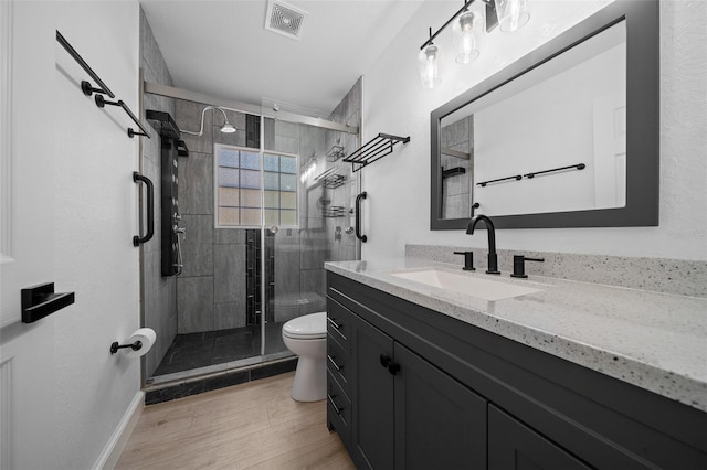 full bath with a stall shower, toilet, baseboards, visible vents, and vanity