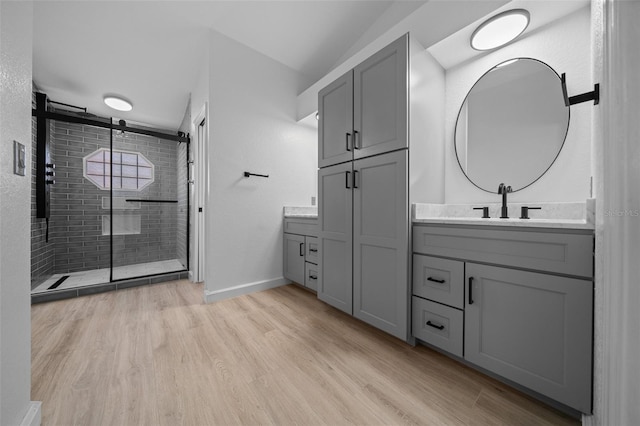 full bathroom featuring a shower stall, lofted ceiling, wood finished floors, vanity, and baseboards