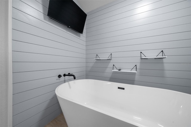 bathroom with wood walls and a soaking tub
