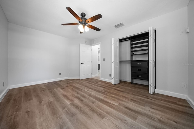 unfurnished bedroom with baseboards, wood finished floors, and visible vents