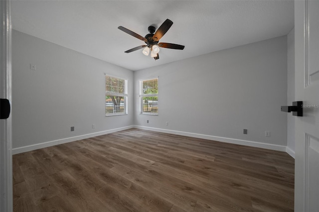 empty room featuring baseboards, ceiling fan, and dark wood finished floors