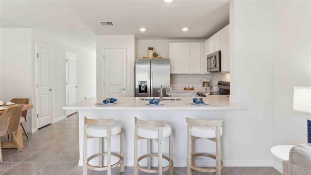 6591 SW 81st Loop, Ocala, FL 34476 - kitchen featuring stainless steel appliances, a peninsula, light countertops, and a kitchen bar
