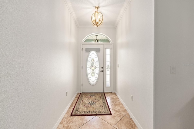 foyer entrance featuring light tile patterned flooring, baseboards, ornamental molding, and an inviting chandelier