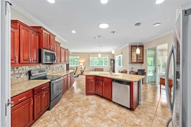 kitchen featuring crown molding, appliances with stainless steel finishes, a sink, and a kitchen island with sink
