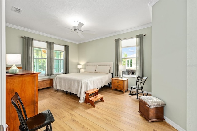 bedroom featuring a ceiling fan, visible vents, light wood-style floors, and ornamental molding