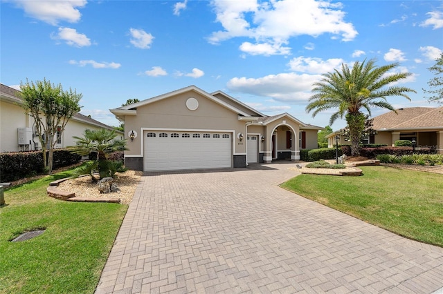 view of front of property featuring stucco siding, decorative driveway, a front yard, and a garage